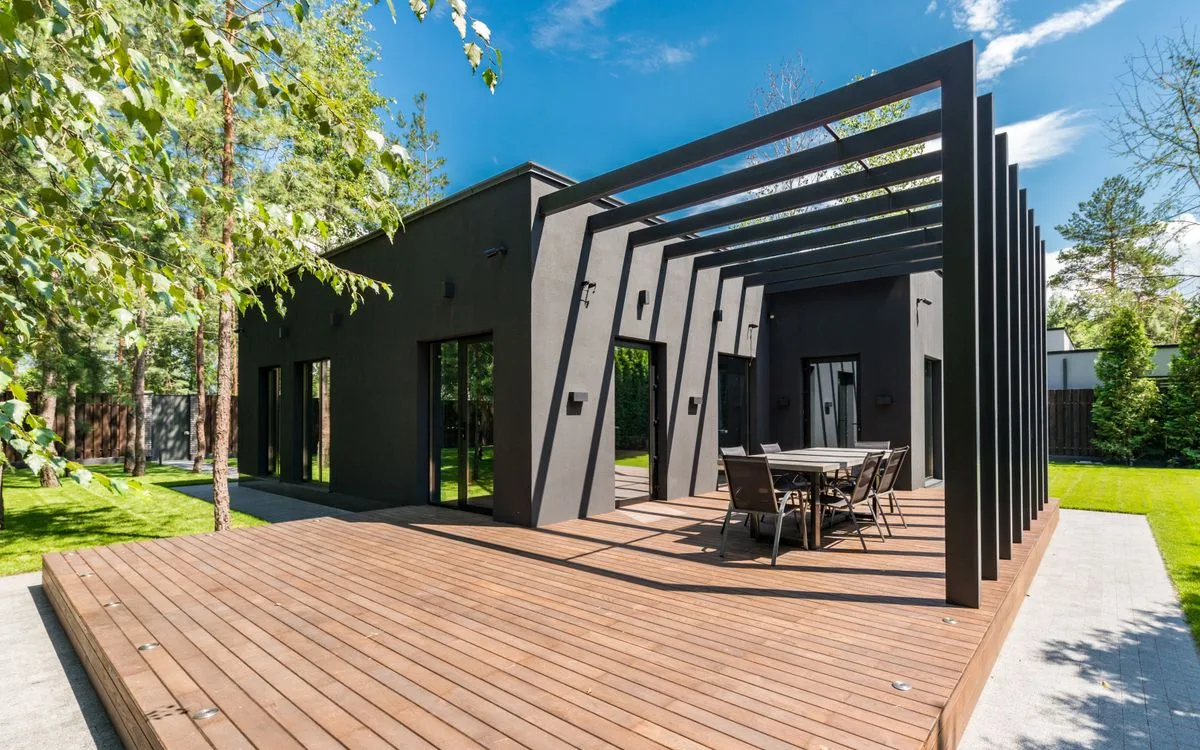 Newly built wooden deck with a steel pergola beside a modern home