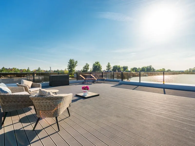 Wide timber deck with outdoor furniture beside open water