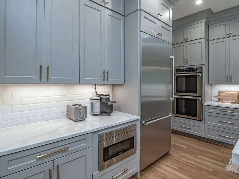 Renovated kitchen with grey cabinets, quartz counters and a tile backsplash